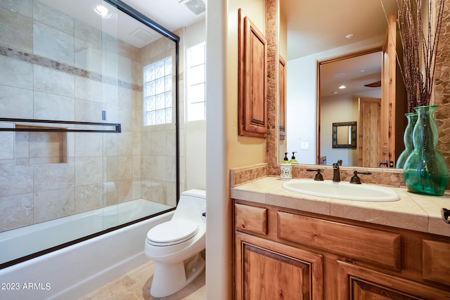 full bathroom with combined bath / shower with glass door, vanity, and toilet