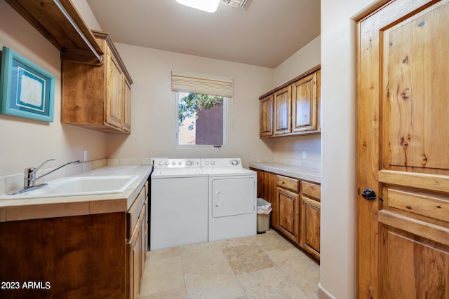 clothes washing area with washer and dryer, sink, and cabinets