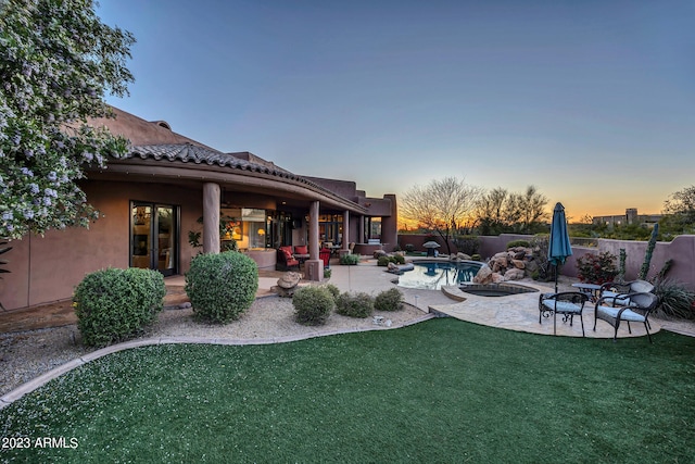 yard at dusk with a fire pit, a patio area, and a fenced in pool