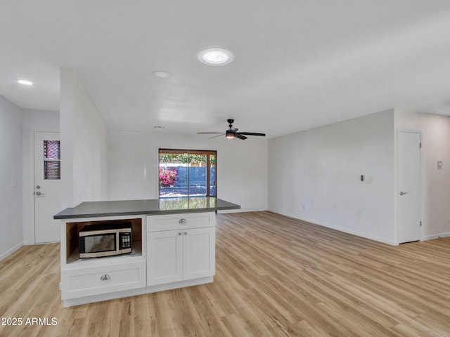 kitchen with light wood-type flooring, ceiling fan, and white cabinets