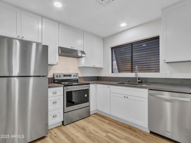 kitchen with appliances with stainless steel finishes, light hardwood / wood-style flooring, white cabinetry, and sink