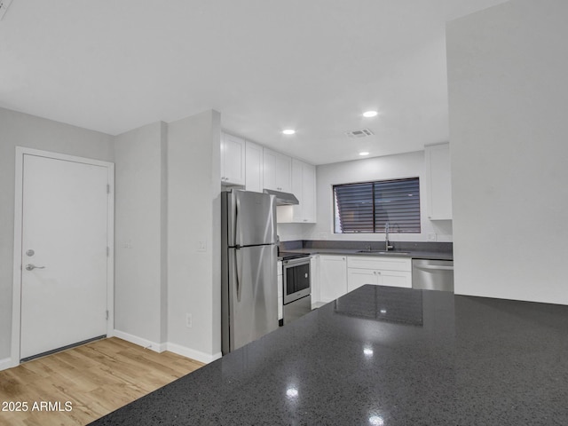 kitchen with white cabinets, sink, dark stone countertops, and stainless steel appliances