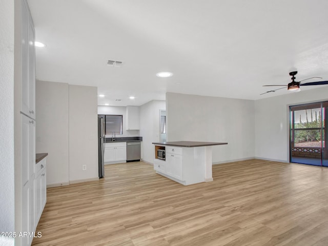 kitchen with ceiling fan, white cabinets, light wood-type flooring, and stainless steel appliances