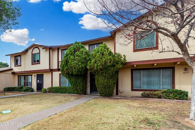 multi unit property featuring a front lawn and stucco siding