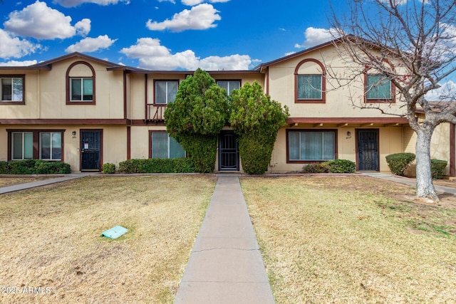 view of property with a front lawn and stucco siding