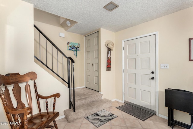 foyer featuring stairway, a textured ceiling, baseboards, and light tile patterned floors