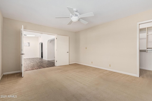 unfurnished bedroom featuring a walk in closet, a closet, ceiling fan, and carpet flooring