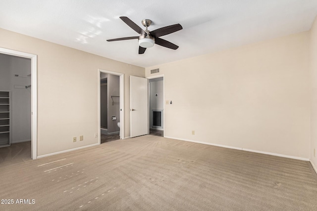 unfurnished bedroom featuring ensuite bathroom, carpet floors, a walk in closet, ceiling fan, and a closet