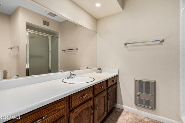 bathroom featuring vanity, a shower with shower door, and heating unit