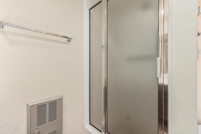 bathroom featuring heating unit and an enclosed shower