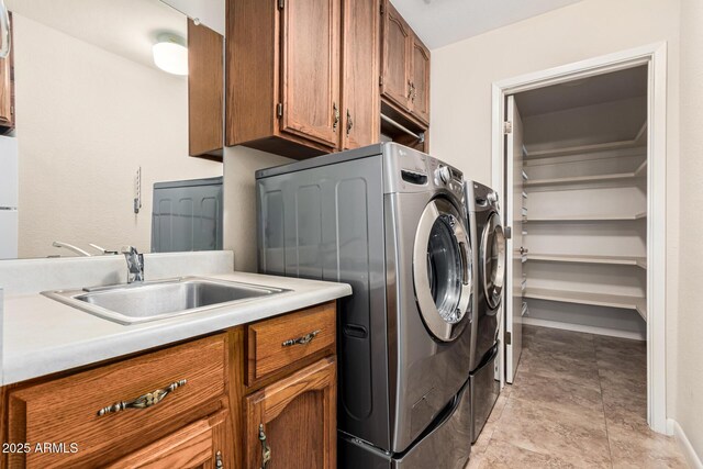 laundry area featuring sink, light tile patterned floors, washing machine and dryer, and cabinets