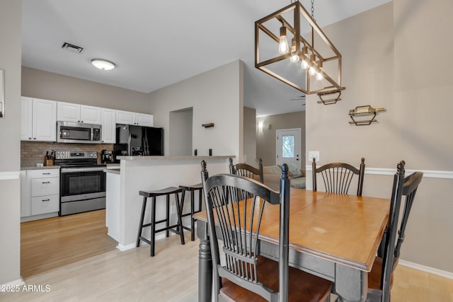 dining room featuring light wood-type flooring, baseboards, and visible vents