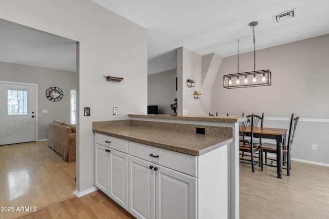 kitchen featuring light wood-style floors, baseboards, white cabinetry, and visible vents