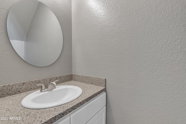 bathroom with a textured wall and vanity