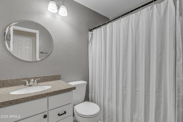 bathroom with vanity, a textured wall, toilet, and curtained shower