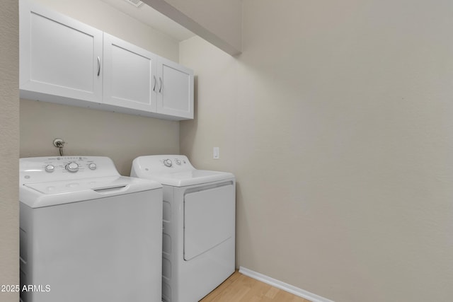 laundry room featuring cabinet space, baseboards, washing machine and dryer, and light wood-style flooring
