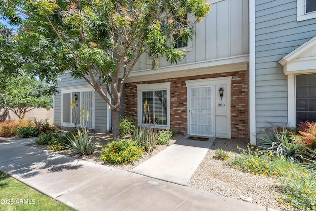 view of exterior entry featuring board and batten siding and brick siding