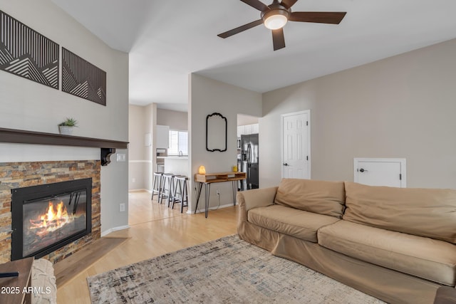living area featuring ceiling fan, wood finished floors, and a fireplace