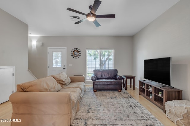 living area featuring ceiling fan, light wood-type flooring, and visible vents
