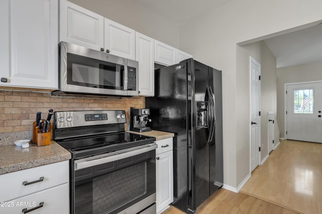 kitchen with backsplash, white cabinets, appliances with stainless steel finishes, and light wood-type flooring