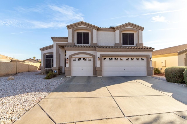 mediterranean / spanish-style home with a garage, fence, a tile roof, concrete driveway, and stucco siding