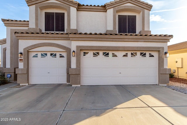 view of front facade featuring a garage, concrete driveway, a tile roof, and stucco siding