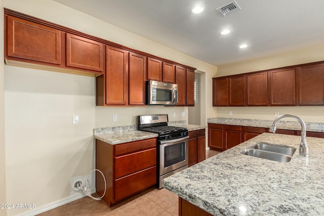 kitchen featuring light stone countertops, sink, light tile patterned flooring, and appliances with stainless steel finishes