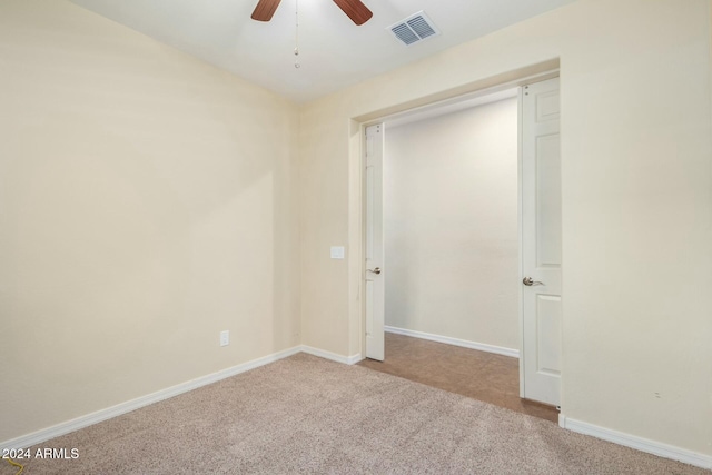 unfurnished bedroom featuring a closet, light colored carpet, and ceiling fan