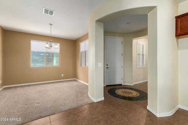 tiled entryway featuring a notable chandelier