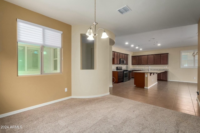 kitchen featuring dark carpet, a kitchen bar, a kitchen island with sink, and appliances with stainless steel finishes