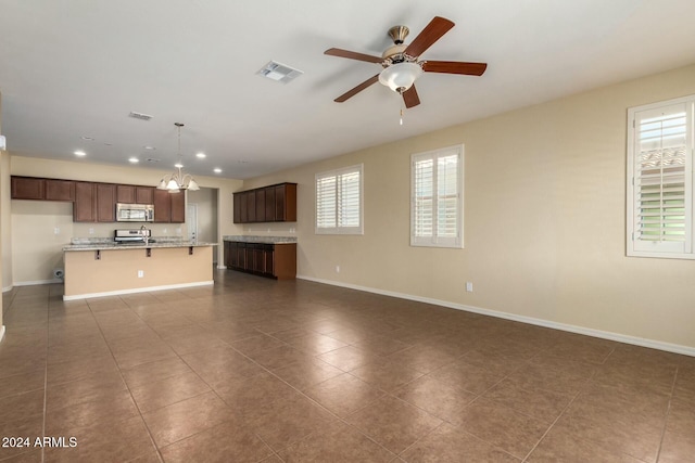 unfurnished living room with dark tile patterned flooring and ceiling fan with notable chandelier