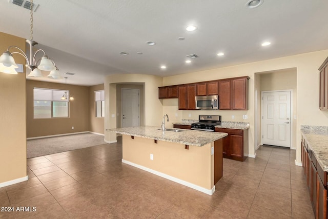 kitchen featuring light stone countertops, appliances with stainless steel finishes, a breakfast bar, sink, and a chandelier