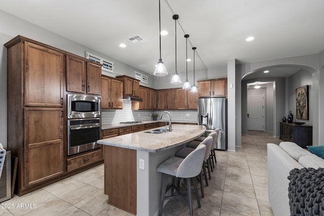 8633 E Kael Cir, Mesa, AZ 85207 - kitchen with appliances with stainless steel finishes, a sink, arched walkways, a kitchen breakfast bar, and tasteful backsplash