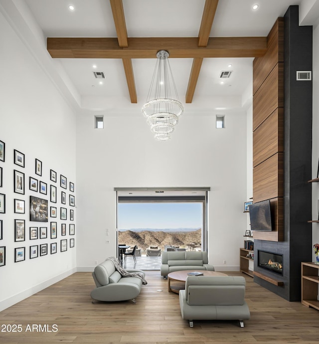 living room featuring hardwood / wood-style flooring, a fireplace, a chandelier, and a high ceiling