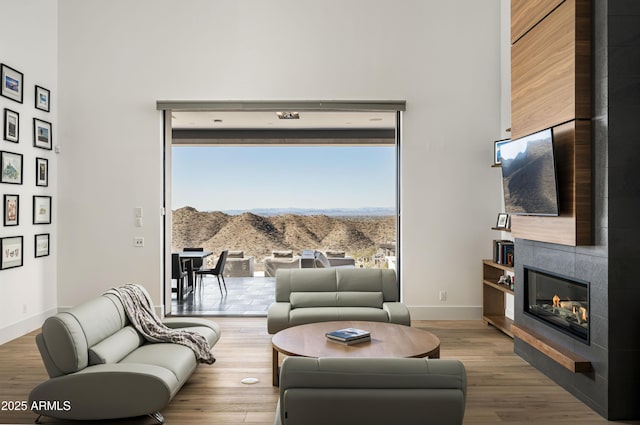 living room featuring hardwood / wood-style flooring, a tiled fireplace, and a high ceiling