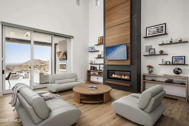 living room with a high ceiling, a mountain view, a fireplace, and light wood-type flooring