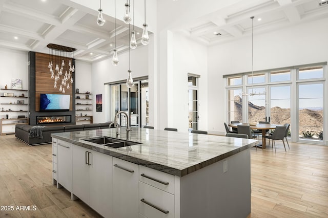 kitchen featuring decorative light fixtures, sink, white cabinets, a mountain view, and a center island with sink