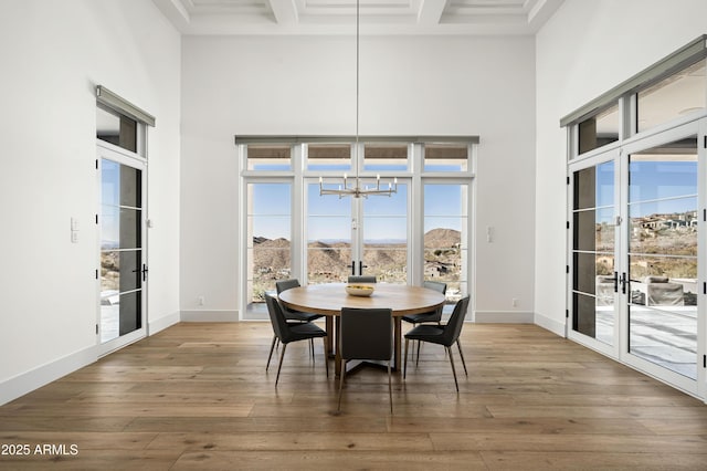 dining area featuring french doors, coffered ceiling, dark hardwood / wood-style flooring, beamed ceiling, and a towering ceiling