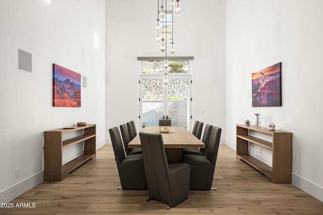 dining room featuring a high ceiling, hardwood / wood-style floors, and a notable chandelier