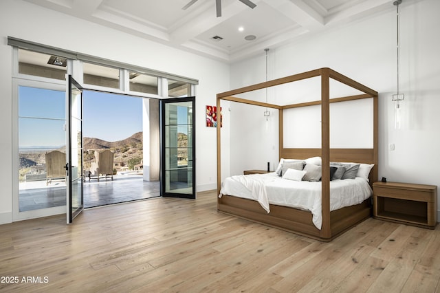 bedroom featuring beamed ceiling, coffered ceiling, access to exterior, a mountain view, and light hardwood / wood-style flooring