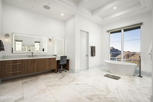 bathroom featuring a towering ceiling, beam ceiling, a bathtub, vanity, and a mountain view