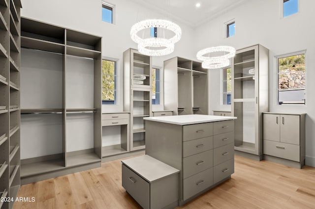 spacious closet featuring a high ceiling, a chandelier, and light wood-type flooring