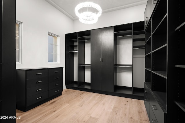 walk in closet with light wood-type flooring and a chandelier