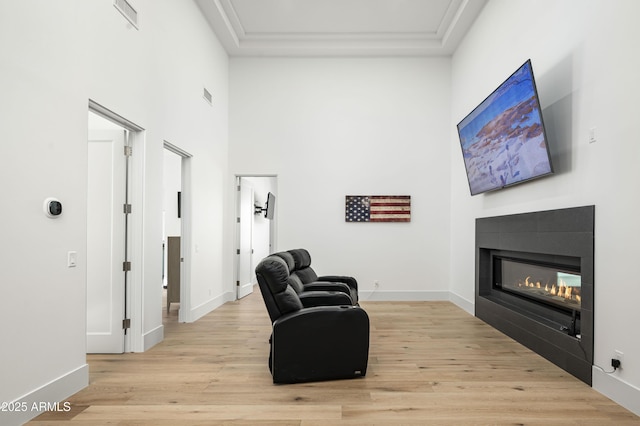 sitting room with a towering ceiling and light hardwood / wood-style floors