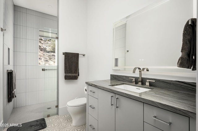 bathroom with vanity, toilet, and tiled shower