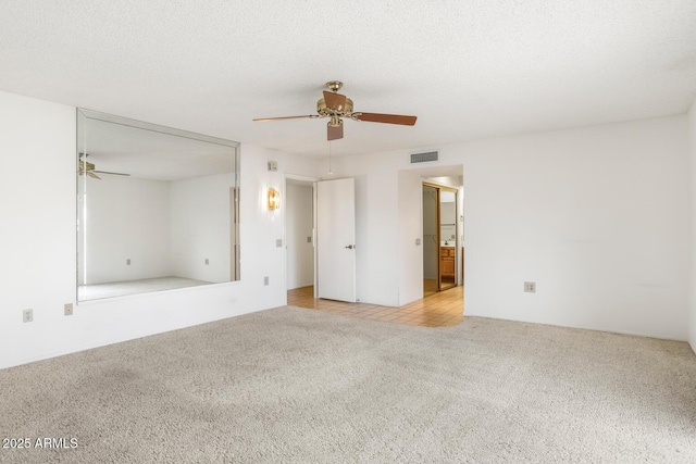 carpeted spare room featuring ceiling fan and a textured ceiling