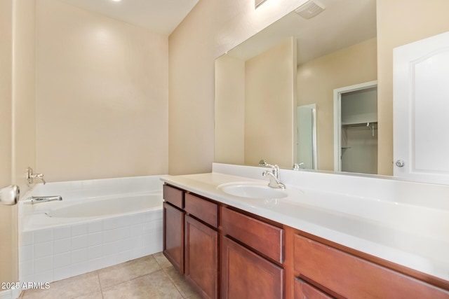 bathroom with tile patterned flooring, tiled tub, and vanity