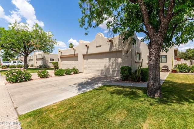 pueblo-style house with concrete driveway, stucco siding, an attached garage, and a front lawn
