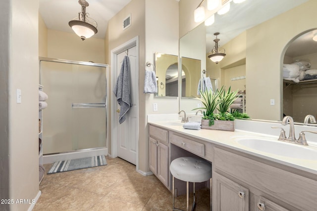 full bath with a stall shower, visible vents, a sink, and double vanity
