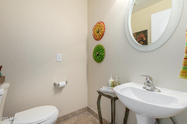 bathroom featuring toilet, tile patterned flooring, a sink, and baseboards